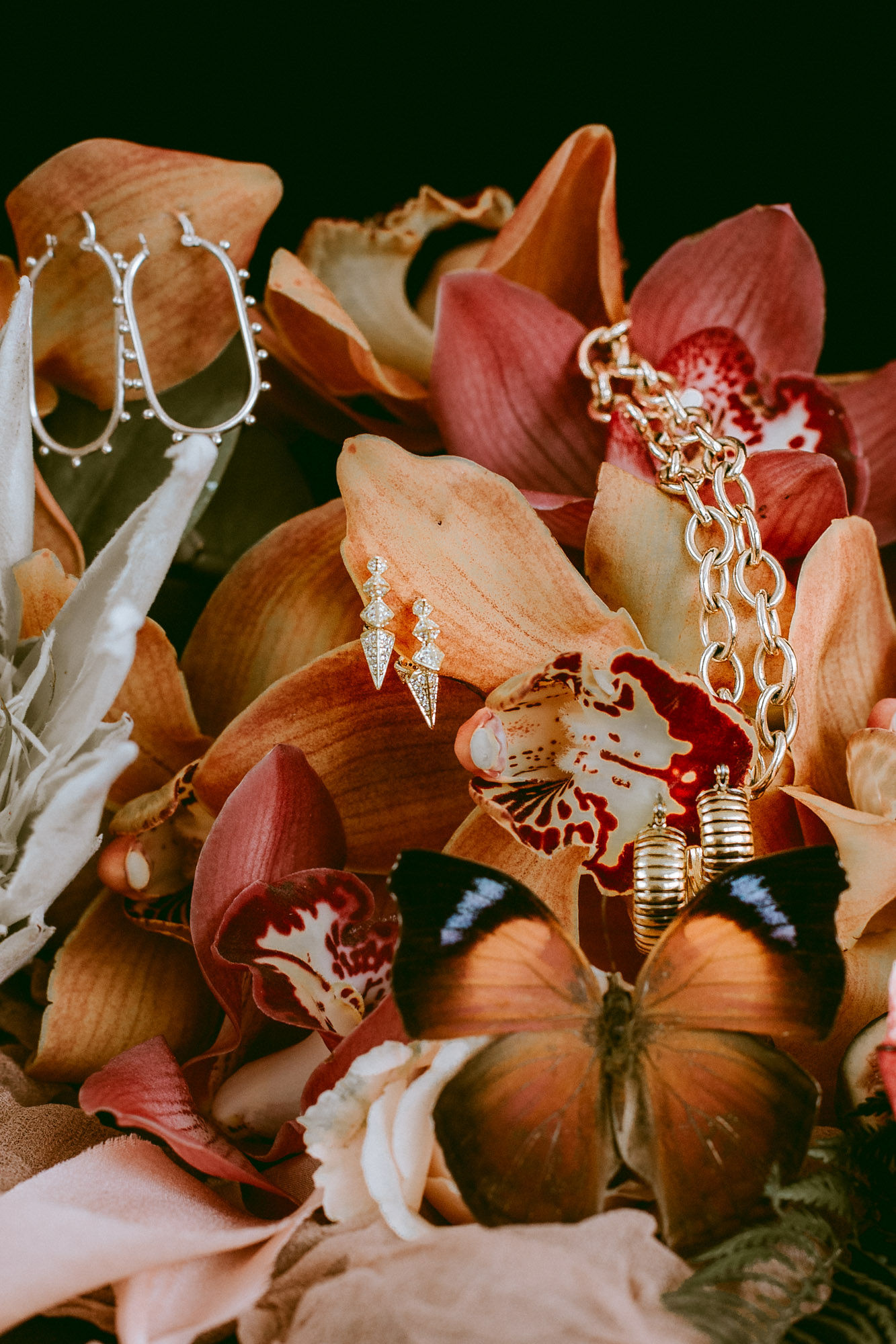 A jewelry still life arranged with flowers and fine metal